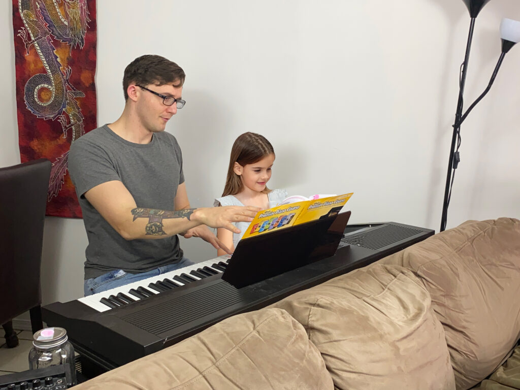 Kelowna Piano teacher Alex Stacey teaching a young girl the piano.